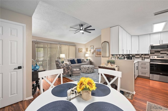 dining room featuring a ceiling fan, dark wood-type flooring, lofted ceiling, and a textured ceiling