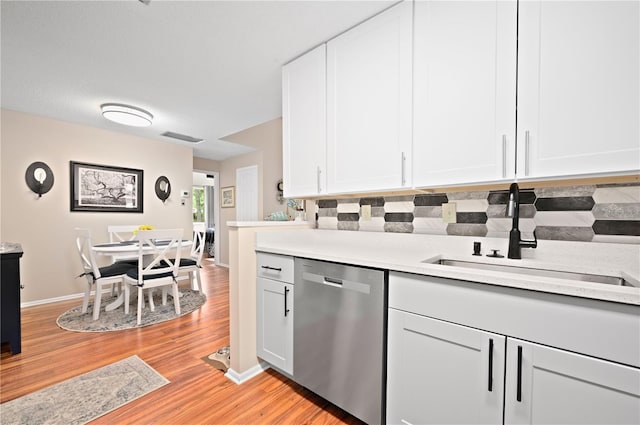 kitchen with dishwasher, a sink, light countertops, light wood-style flooring, and white cabinetry