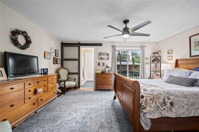 bedroom featuring access to outside, a barn door, a textured ceiling, and a ceiling fan