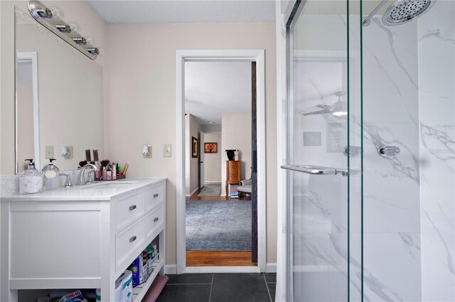 full bath featuring a marble finish shower, vanity, and tile patterned flooring