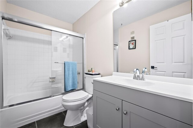 full bathroom with vanity, toilet, shower / bath combination with glass door, and tile patterned flooring
