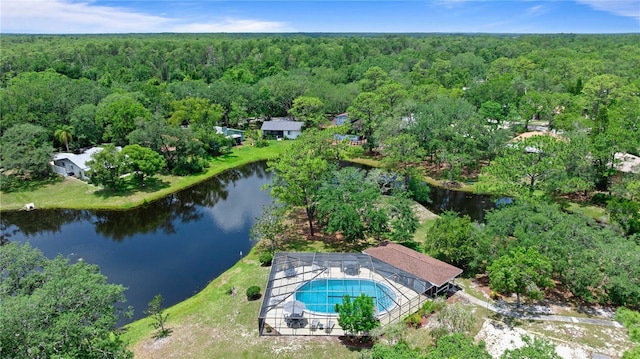 bird's eye view of a heavily wooded area, a pool, and a large body of water