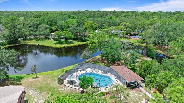 bird's eye view of a heavily wooded area, a large body of water, and a pool area