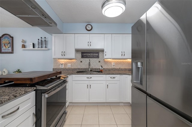 2222 Ocean Shore Blvd Unit 304B, Ormond Beach, FL 32176 - kitchen with appliances with stainless steel finishes, ventilation hood, white cabinets, light tile patterned floors, and a textured ceiling
