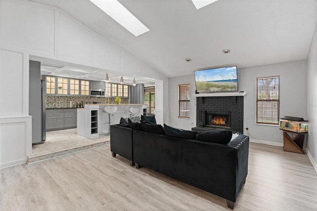 901 Vicksburg St, Deltona, FL 32725 - living room featuring light wood-style flooring, a fireplace, a skylight, high vaulted ceiling, and baseboards