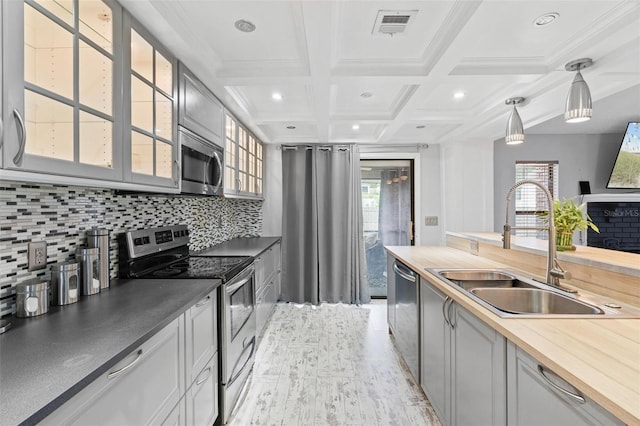 901 Vicksburg St, Deltona, FL 32725 - kitchen featuring appliances with stainless steel finishes, a sink, glass insert cabinets, coffered ceiling, and backsplash