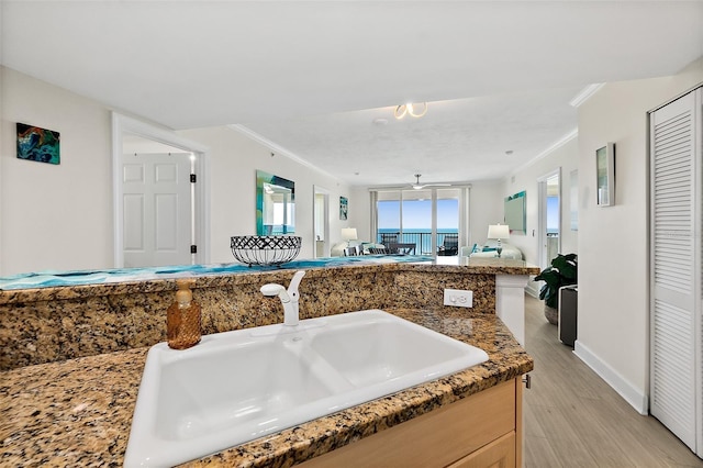 3315 S Atlantic Ave Unit 1406, Daytona Beach Shores, FL 32118 - kitchen featuring crown molding, a sink, open floor plan, light wood finished floors, and baseboards