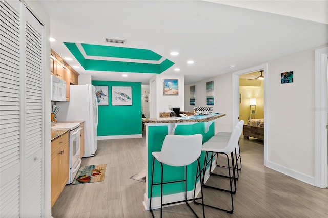 3315 S Atlantic Ave Unit 1406, Daytona Beach Shores, FL 32118 - kitchen featuring white appliances, a breakfast bar, light wood-style floors, baseboards, and recessed lighting