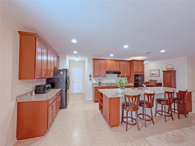 110 No Name Key Dr, Deland, FL 32720 - kitchen with black appliances, recessed lighting, under cabinet range hood, a kitchen breakfast bar, and a large island with sink