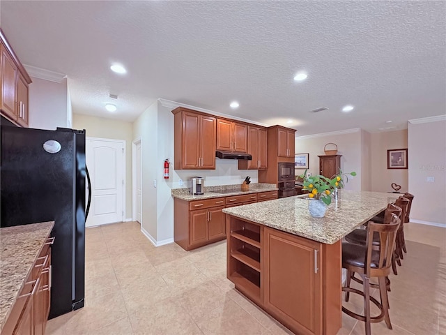 110 No Name Key Dr, Deland, FL 32720 - kitchen with black appliances, a center island, baseboards, light stone counters, and ornamental molding