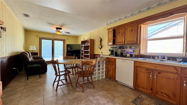 1301 Killian St, Daytona Beach, FL 32114 - kitchen featuring dishwasher, a sink, tile counters, healthy amount of natural light, and wood walls