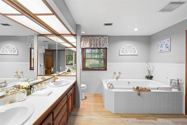 1056 Reynolds Rd, De Leon Springs, FL 32130 - bathroom with toilet, double vanity, a bath, and wood finished floors