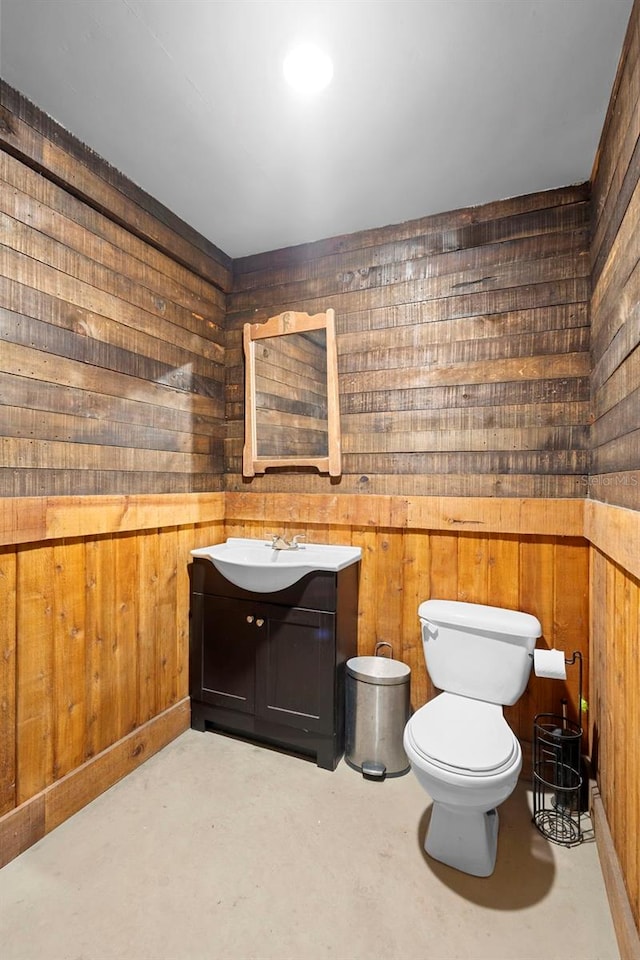 1056 Reynolds Rd, De Leon Springs, FL 32130 - half bathroom with wood walls, toilet, vanity, and concrete floors