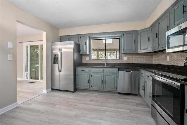 2032 Yorkshire Dr, Deland, FL 32724 - kitchen featuring appliances with stainless steel finishes, dark countertops, tasteful backsplash, light wood-type flooring, and a textured ceiling