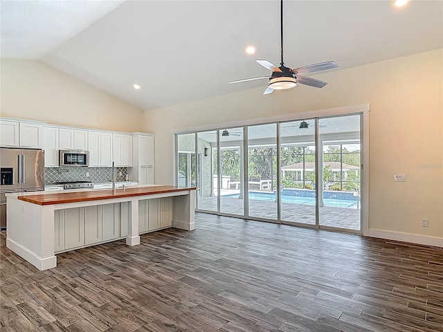 1520 Stone Trl, Enterprise, FL 32725 - kitchen with wood counters, stainless steel appliances, dark wood-type flooring, vaulted ceiling, and backsplash