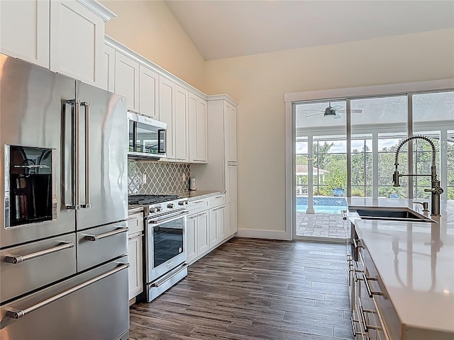 1520 Stone Trl, Enterprise, FL 32725 - kitchen with high end appliances, backsplash, dark wood-style flooring, white cabinets, and lofted ceiling