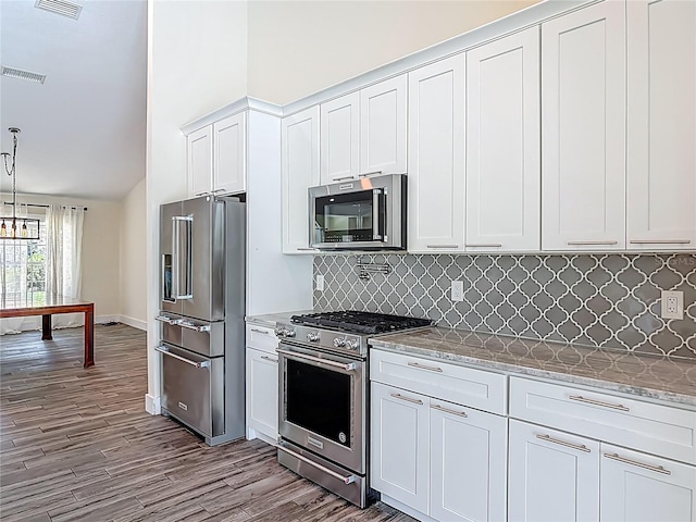 1520 Stone Trl, Enterprise, FL 32725 - kitchen with appliances with stainless steel finishes, dark wood-type flooring, tasteful backsplash, white cabinetry, and lofted ceiling