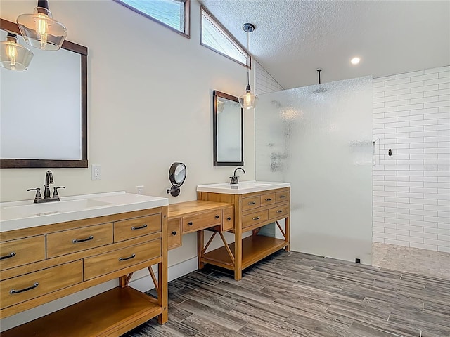 1520 Stone Trl, Enterprise, FL 32725 - bathroom featuring a walk in shower, wood finished floors, two vanities, vaulted ceiling, and a textured ceiling