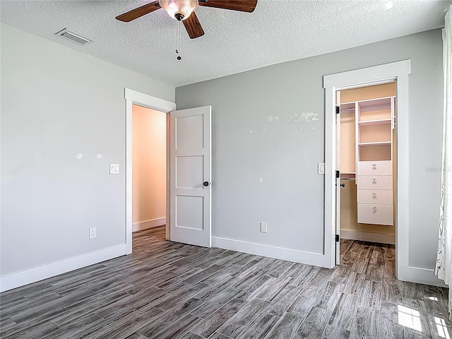 1520 Stone Trl, Enterprise, FL 32725 - unfurnished bedroom with wood finished floors, a spacious closet, a textured ceiling, baseboards, and a closet