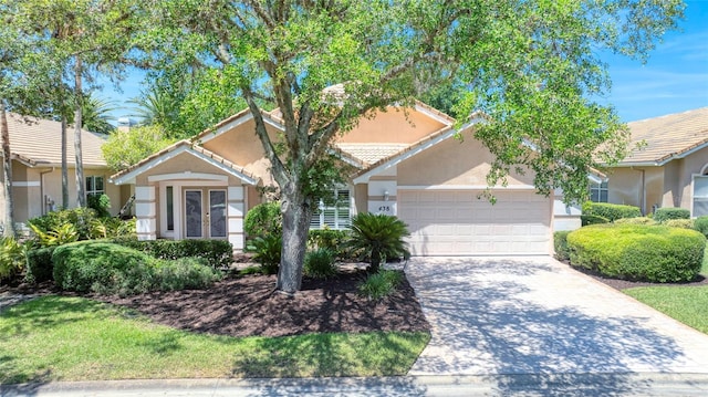 438 Harbour Town Ln, Ormond Beach, FL 32174 - view of property hidden behind natural elements with an attached garage, stucco siding, driveway, french doors, and a tiled roof