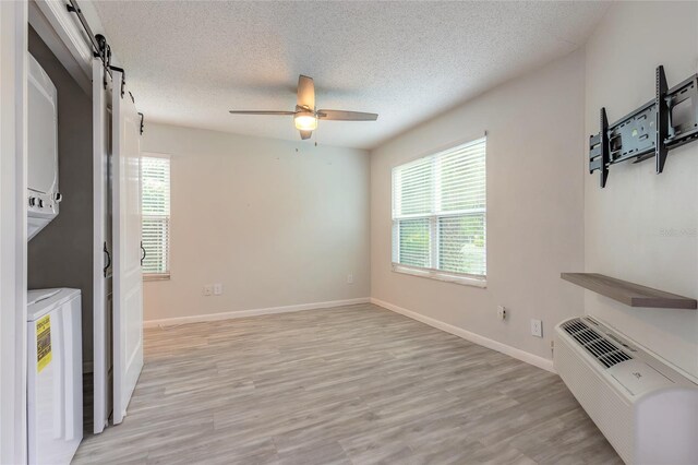 1401 S Palmetto Ave Unit 119, Daytona Beach, FL 32114 - unfurnished living room featuring plenty of natural light, a barn door, light wood-style flooring, and a textured ceiling