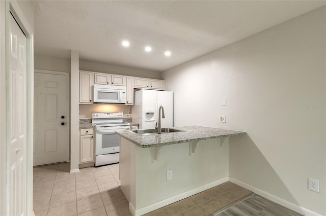 1401 S Palmetto Ave Unit 119, Daytona Beach, FL 32114 - kitchen featuring white appliances, a peninsula, a sink, a breakfast bar, and light stone countertops