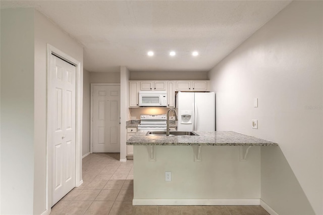 1401 S Palmetto Ave Unit 119, Daytona Beach, FL 32114 - kitchen featuring white appliances, a sink, a kitchen bar, light stone counters, and a peninsula