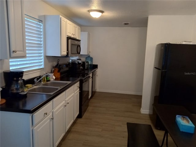 20422 Canvas Back Rd, Altoona, FL 32702 - kitchen with black / electric stove, a sink, freestanding refrigerator, dark countertops, and white cabinetry