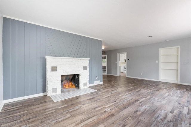 1411 Cliff Ave, Eustis, FL 32726 - unfurnished living room featuring wood finished floors, built in shelves, a brick fireplace, and baseboards