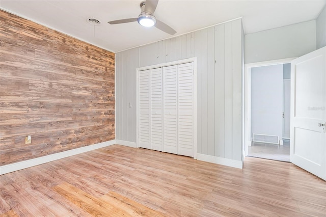 1411 Cliff Ave, Eustis, FL 32726 - unfurnished bedroom featuring wood walls, light wood-style flooring, baseboards, a closet, and ceiling fan