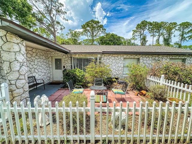 1229 Jeffery Dr, Port Orange, FL 32129 - view of front of property featuring stone siding, a fenced front yard, a patio, and a shingled roof