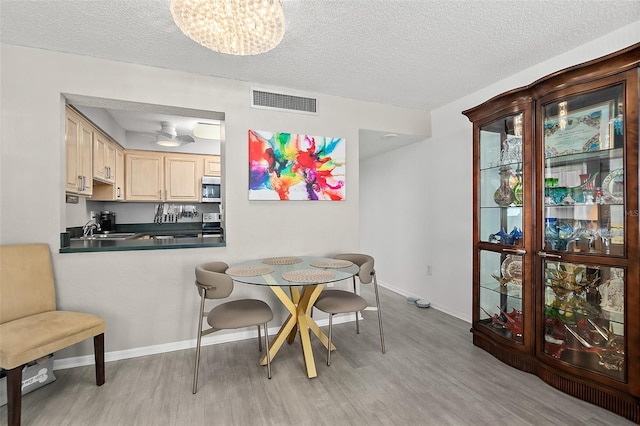2987 S Atlantic Ave Unit 901, Daytona Beach, FL 32118 - dining room featuring light wood-style floors, a textured ceiling, and a chandelier