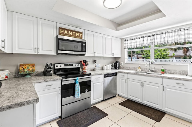 833 Lucerne Cir, Ormond Beach, FL 32174 - kitchen with appliances with stainless steel finishes, a raised ceiling, a sink, light tile patterned floors, and white cabinetry
