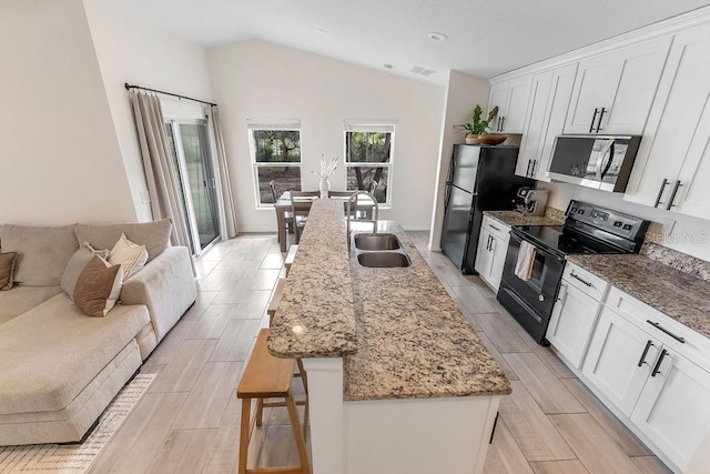 1092 Gage Ave, Deltona, FL 32738 - kitchen with black range with electric stovetop, stainless steel microwave, a sink, lofted ceiling, and wood finish floors