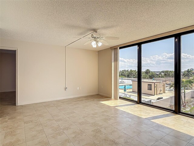1 Oceans W Blvd Unit 2A1, Daytona Beach, FL 32118 - unfurnished room featuring healthy amount of natural light, ceiling fan, a textured ceiling, baseboards, and expansive windows