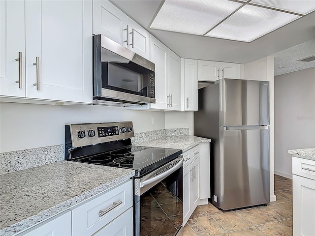 1 Oceans W Blvd Unit 2A1, Daytona Beach, FL 32118 - kitchen with stainless steel appliances, white cabinetry, light stone counters, and baseboards