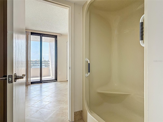 1 Oceans W Blvd Unit 2A1, Daytona Beach, FL 32118 - full bath featuring tile patterned floors, a textured ceiling, a shower, expansive windows, and baseboards