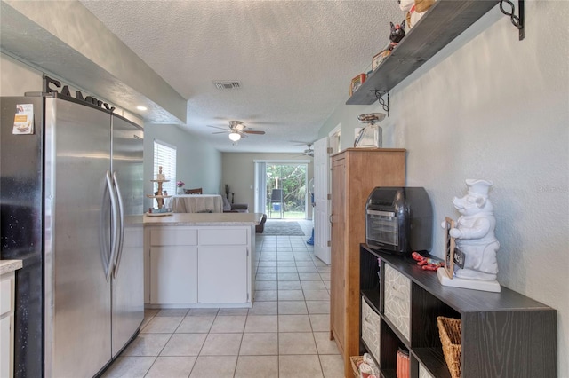 721 Laurel Bay Cir, New Smyrna Beach, FL 32169 - kitchen with freestanding refrigerator, a ceiling fan, a textured ceiling, white cabinets, and light tile patterned floors