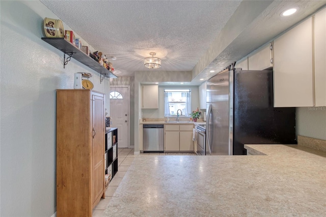 721 Laurel Bay Cir, New Smyrna Beach, FL 32169 - kitchen with stainless steel appliances, open shelves, a textured ceiling, a sink, and light countertops