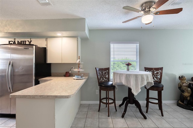 721 Laurel Bay Cir, New Smyrna Beach, FL 32169 - kitchen with freestanding refrigerator, a peninsula, light countertops, light tile patterned flooring, and a ceiling fan