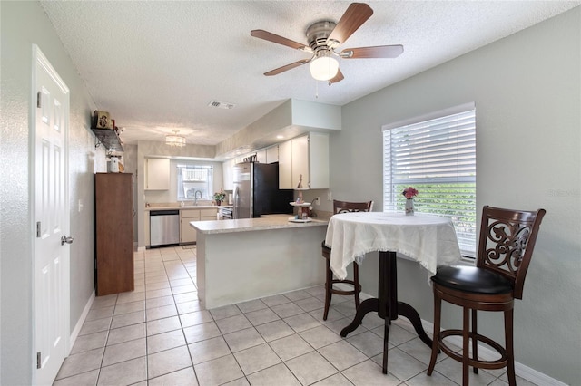 721 Laurel Bay Cir, New Smyrna Beach, FL 32169 - kitchen featuring stainless steel appliances, a peninsula, light countertops, a textured ceiling, and ceiling fan