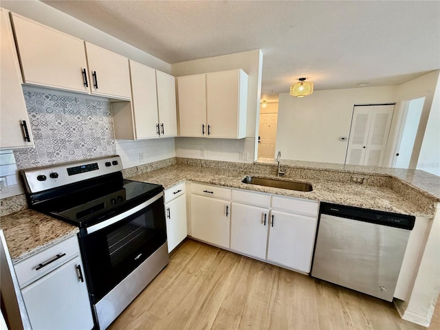 940 Village Trl Unit 8-205, Port Orange, FL 32127 - kitchen featuring stainless steel appliances, light wood-style flooring, tasteful backsplash, a peninsula, and white cabinetry