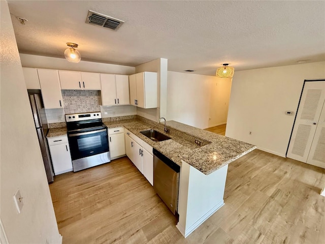 940 Village Trl Unit 8-205, Port Orange, FL 32127 - kitchen featuring appliances with stainless steel finishes, a peninsula, light wood-style floors, white cabinets, and a textured ceiling