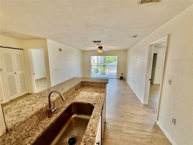 940 Village Trl Unit 8-205, Port Orange, FL 32127 - kitchen featuring light wood-style flooring, light stone countertops, a ceiling fan, a textured ceiling, and open floor plan