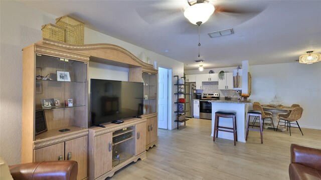 940 Village Trl Unit 8-205, Port Orange, FL 32127 - kitchen featuring appliances with stainless steel finishes, ceiling fan, light wood-style flooring, a kitchen breakfast bar, and a peninsula