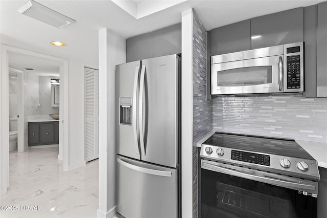 3047 S Atlantic Ave Unit 1805, Daytona Beach, FL 32118 - kitchen with appliances with stainless steel finishes, gray cabinetry, light marble finish flooring, modern cabinets, and tasteful backsplash