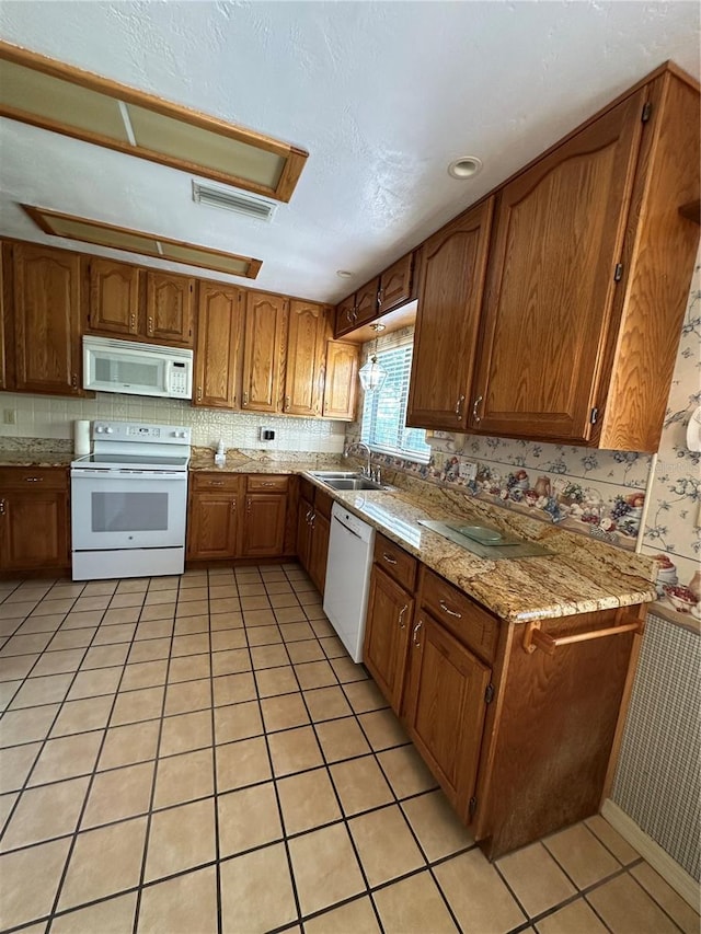 96 Old Barn Trl, Ormond Beach, FL 32174 - kitchen with white appliances, brown cabinets, a sink, light tile patterned flooring, and light stone counters