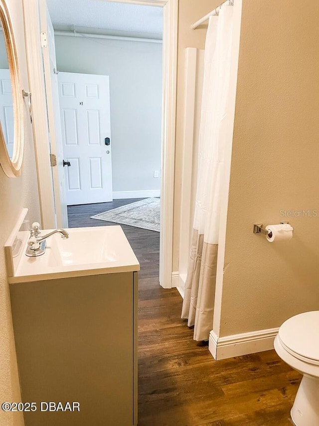 404 S Ridgewood Ave, Daytona Beach, FL 32114 - full bath featuring wood finished floors, toilet, vanity, and baseboards