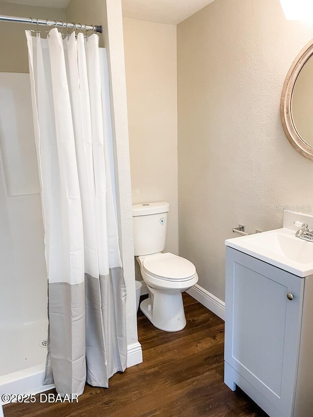 404 S Ridgewood Ave, Daytona Beach, FL 32114 - bathroom featuring wood finished floors, toilet, vanity, curtained shower, and baseboards