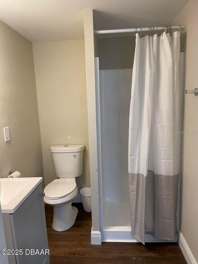 404 S Ridgewood Ave, Daytona Beach, FL 32114 - bathroom with wood finished floors, vanity, toilet, and a shower with shower curtain